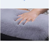 A hand rests on a soft gray plush cushion used as a car armrest or seat accessory.