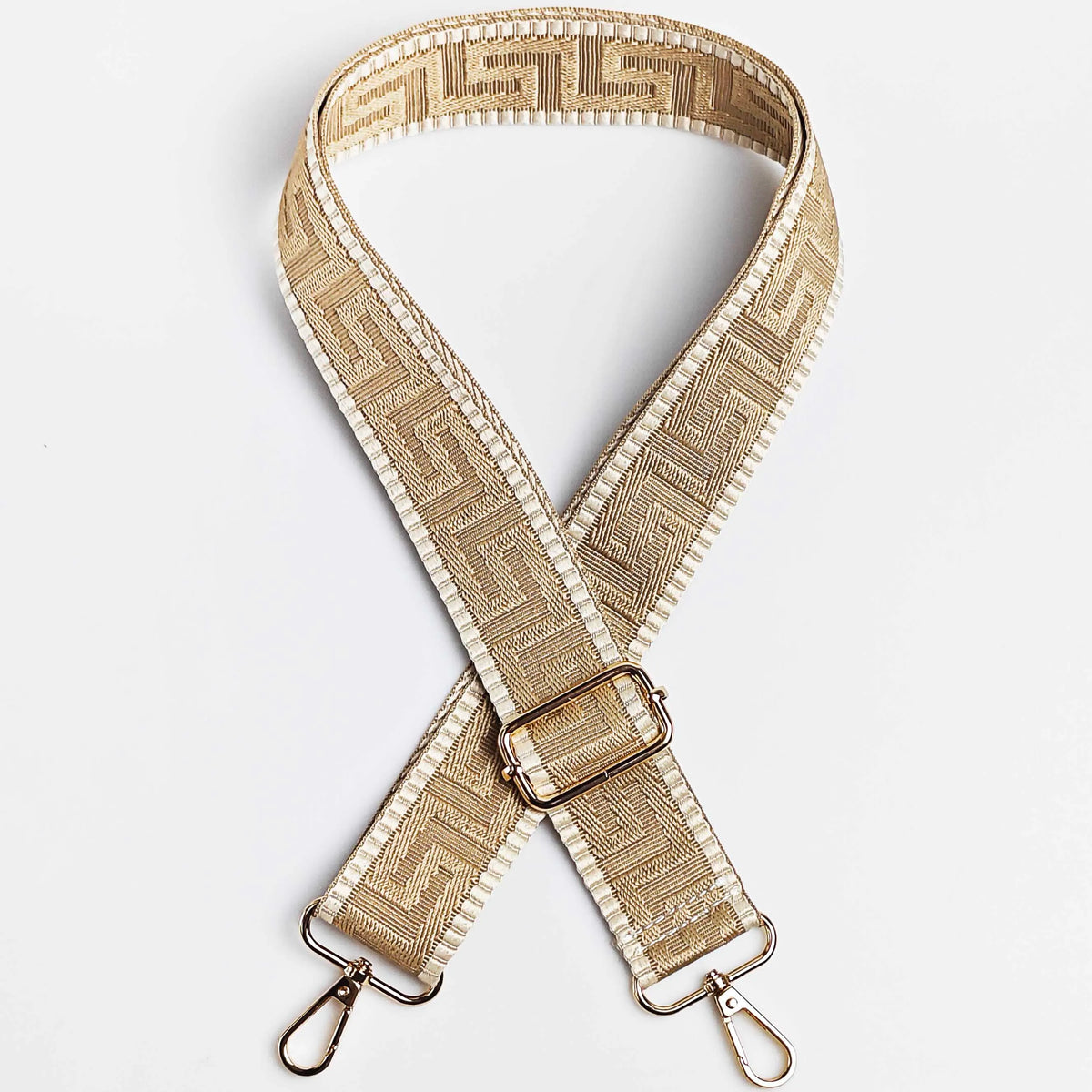 A beige woven strap with a maze pattern is shown folded and crossed, featuring metal hardware.
