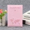 Pochette de passeport en cuir PU rose avec un avion argenté, posée sur une surface grise.