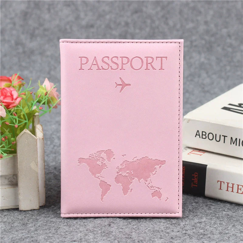 Pochette de passeport en cuir PU rose avec un avion argenté, posée sur une surface grise.