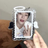 A hand holds a clear acrylic photocard holder with a cartoon angel wing design, featuring a person's face inside.