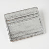 A silver metallic leather card holder with embossed lines and a textured surface.