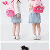 A young girl is holding a pink cartoon rabbit plush backpack.
