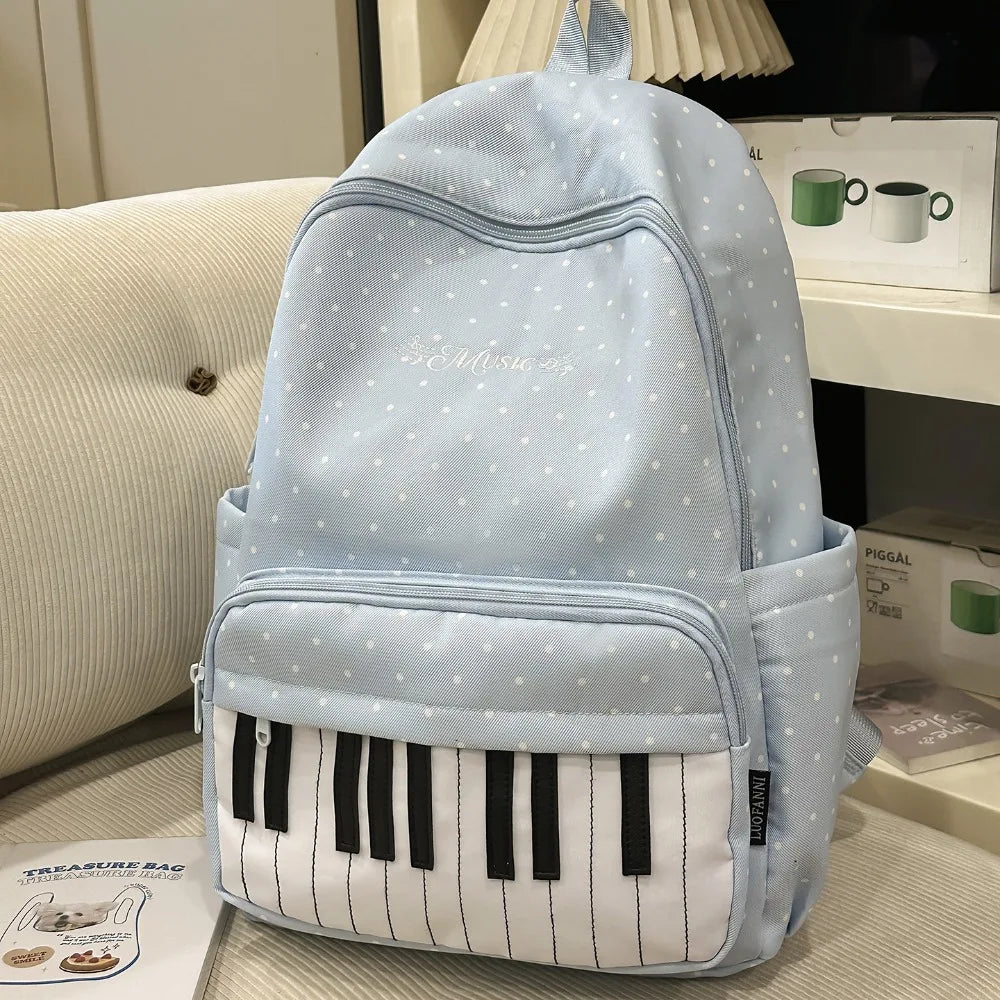 Sac à dos bleu clair à pois avec un motif de touche de piano blanche et des accents noirs.