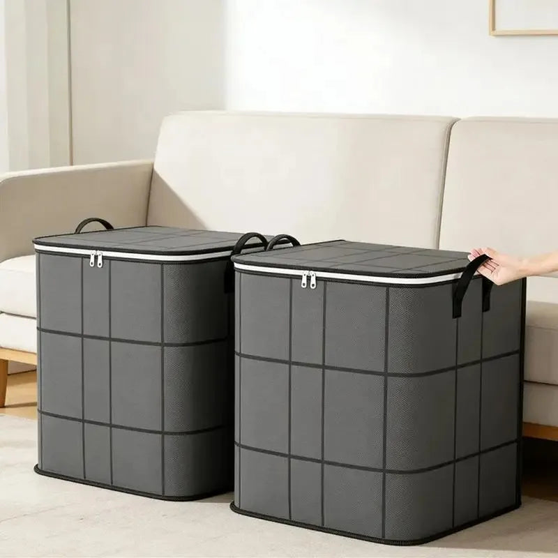Two gray fabric storage bins with black lids are placed on a light-colored floor next to a sofa.