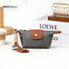 A dark gray compact coin purse made of nylon and faux leather with a brown leather strap and keychain.