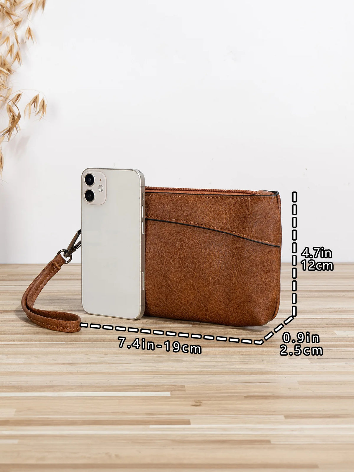 A brown retro PU leather zipper wrist bag next to a white smartphone, shown on a wooden surface.