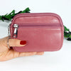 A hand holds a pink PU leather mini wallet with a silver keychain against a white background.