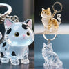A clear glass figurine of a cat in a sitting pose, shown alongside its keychain pendant.