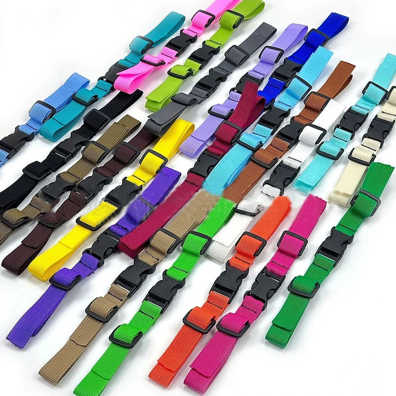 A variety of colorful adjustable tactical backpack chest strap harnesses laid out in a row.