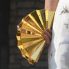A hand holds a gold acrylic chain crossbody bag, displaying its layered, reflective surface.