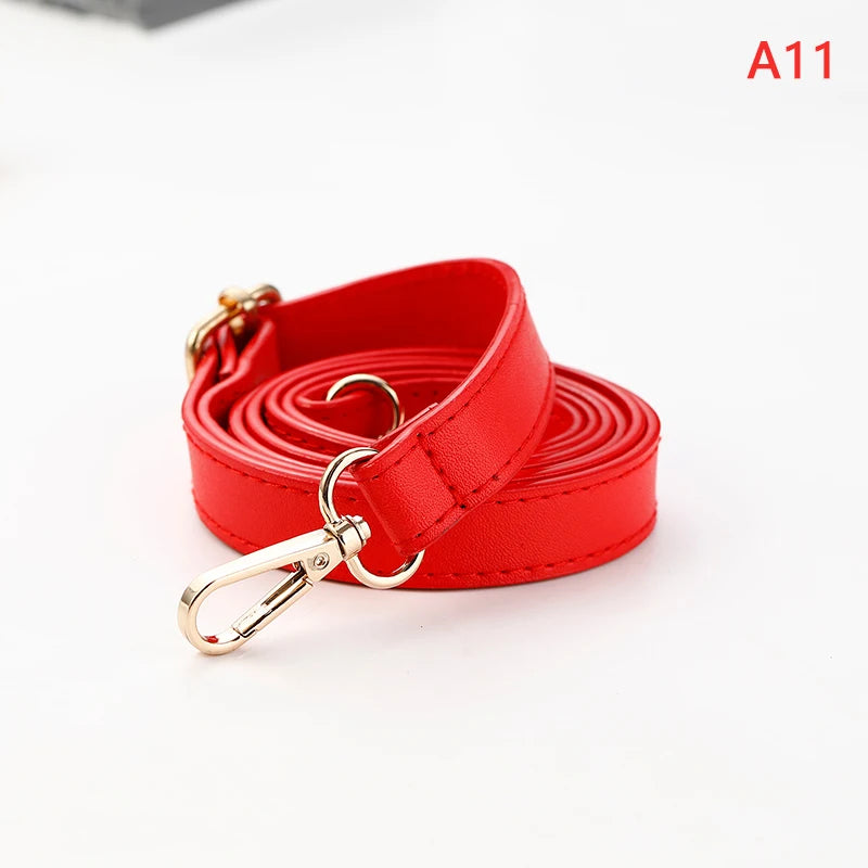A red PU leather crossbody bag strap coiled and featuring a gold-toned metal clasp.