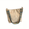 A beige leather crossbody hobo bag with a patterned strap and gold hardware.
