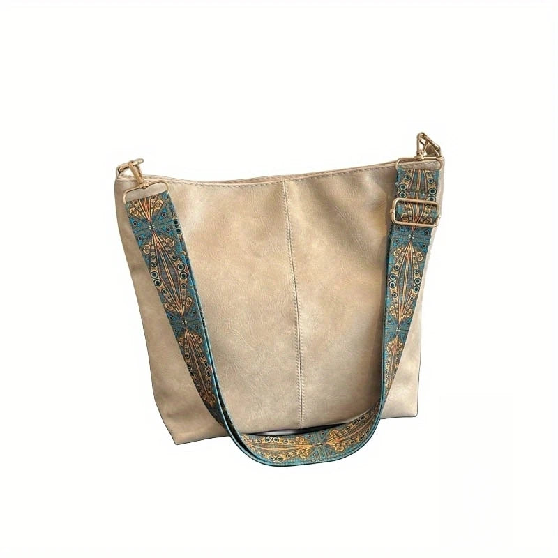 A beige leather crossbody hobo bag with a patterned strap and gold hardware.