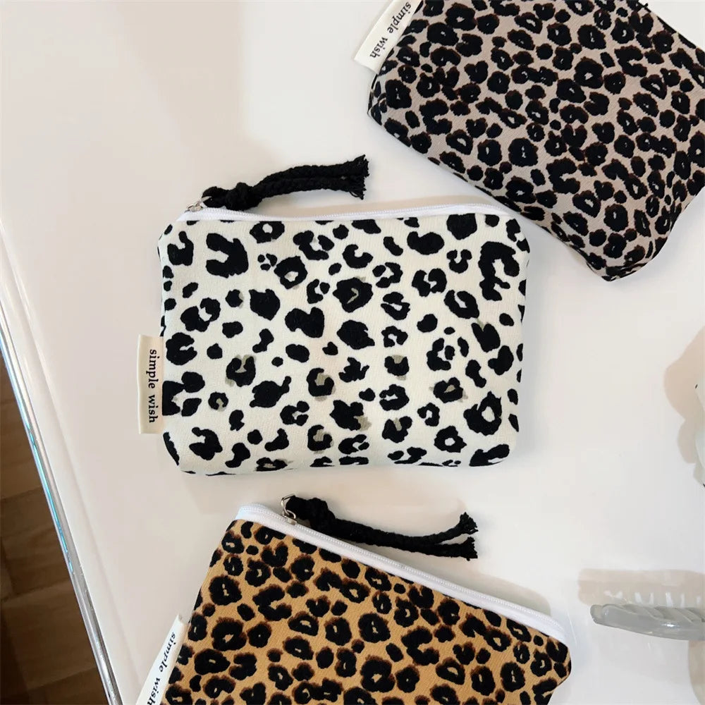A collection of leopard print cosmetic bags in black and white patterns displayed on a white surface.