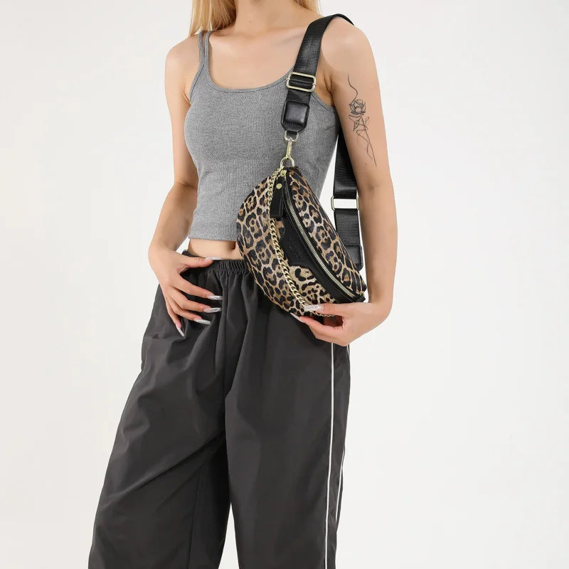 Eine Frau trägt ein graues Tanktop und schwarze Hose und hält eine leopardprintierte Umhängetasche.
