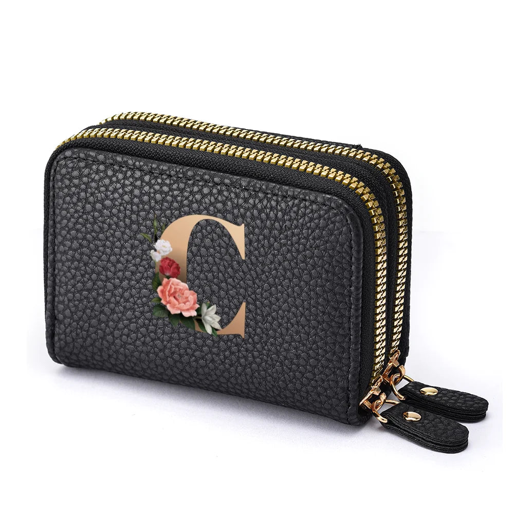 Black faux leather mini wallet with a gold zipper and a rose letter print
