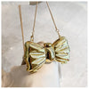 Gold heart-shaped acrylic evening clutch with a delicate chain strap being held by a hand.