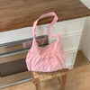 A pink plaid nylon drawstring tote bag resting on a wooden surface.