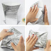A silver insulated thermal food delivery bag with an aluminum foil lining being held by hands.