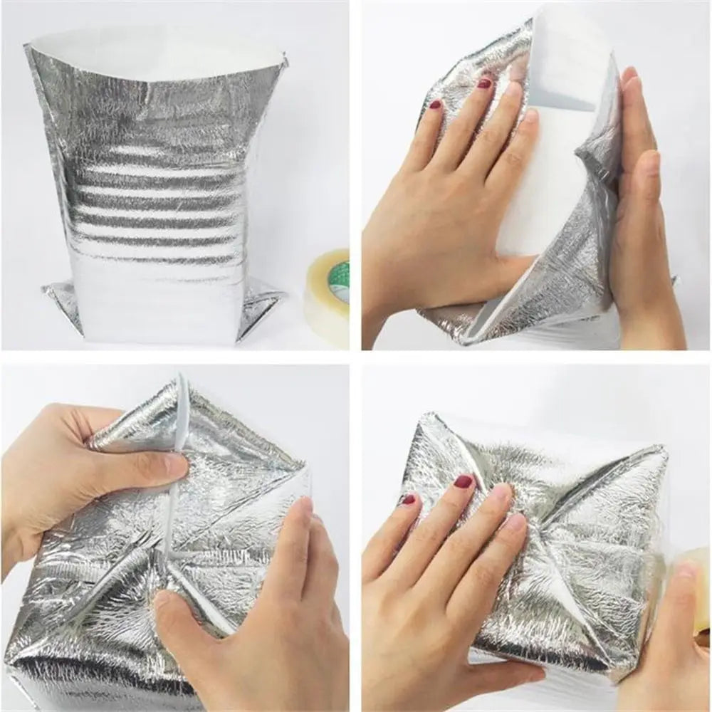 A silver insulated thermal food delivery bag with an aluminum foil lining being held by hands.