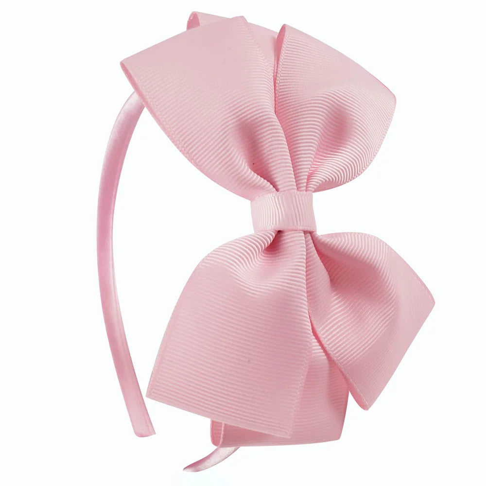 A pink satin bow headband with a ribbon tied in a large bow.