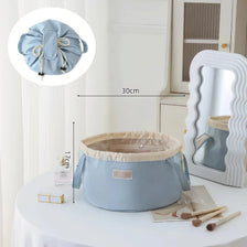 Light blue instant-open flat lay makeup organizer bag with a drawstring closure displayed on a white table.