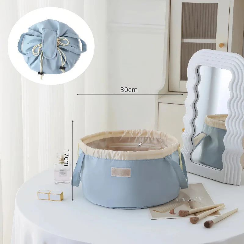 Light blue instant-open flat lay makeup organizer bag with a drawstring closure displayed on a white table.