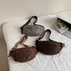 A brown leopard print crossbody bag with adjustable leather straps resting on a white surface.