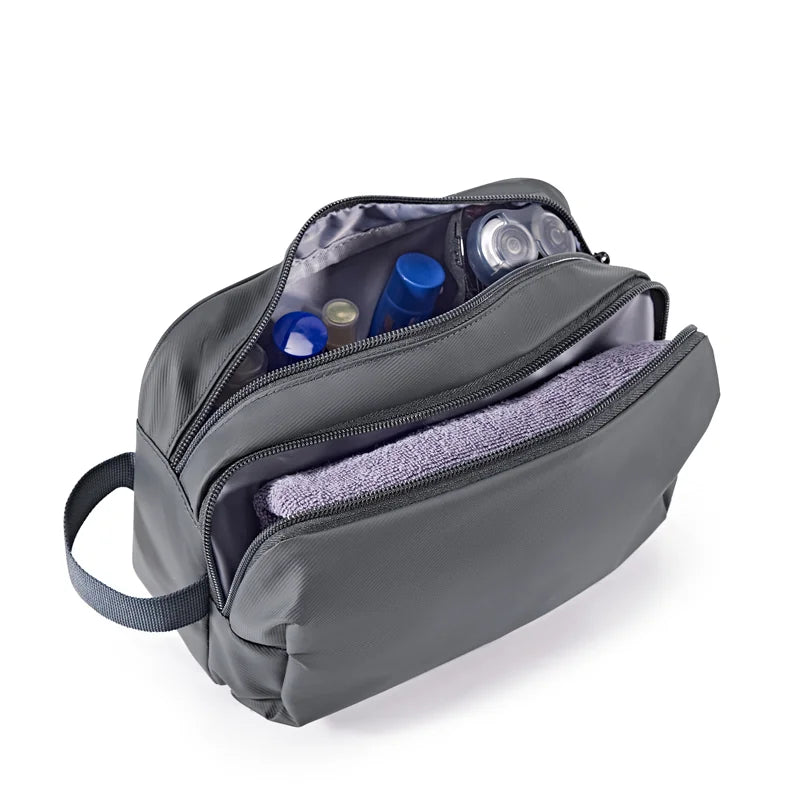 A gray toiletry bag with a zippered compartment and an attached strap, showing various cosmetic bottles inside.