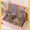 A pink travel makeup organizer bag with an open lid displaying leopard print cosmetic pouches and a brush.
