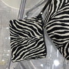 Schwarz-weißes Zebra-Print-Canvas-Crossbody-Taschen, präsentiert auf einem klaren Ständer.