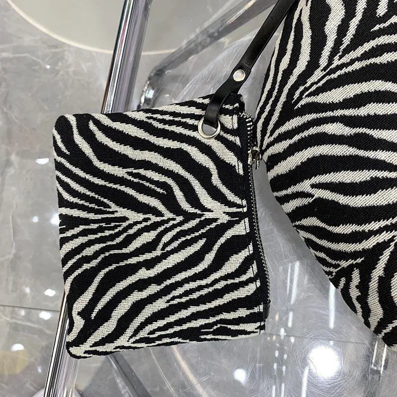 Schwarz-weißes Zebra-Print-Canvas-Crossbody-Taschen, präsentiert auf einem klaren Ständer.
