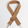 A tan woven leather strap with a maze pattern is shown crossed and laid out on a white background.