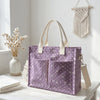 Un sac fourre-tout en velours côtelé violet à pois blancs, exposé sur une table blanche à côté de fleurs séchées.