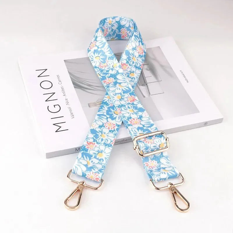 Blue floral patterned diagonal shoulder strap for bags displayed next to a product box.