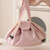 A pink instant-open flat lay makeup organizer bag with light yellow straps is being held by a hand.