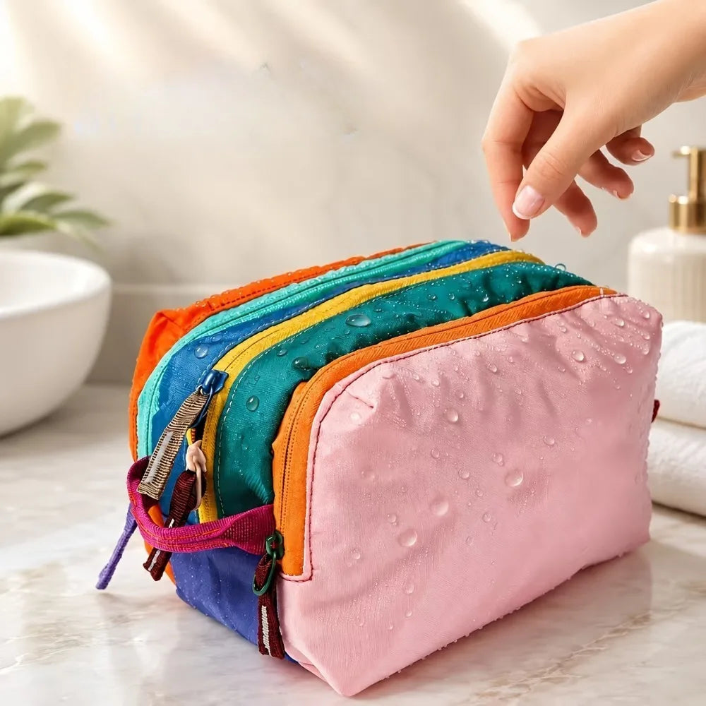 A pink multi-compartment toiletry organizer bag with colorful accents is held by a hand on a marble surface.
