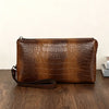 Clutch de estampado de cocodrilo marrón sobre una superficie de madera oscura.