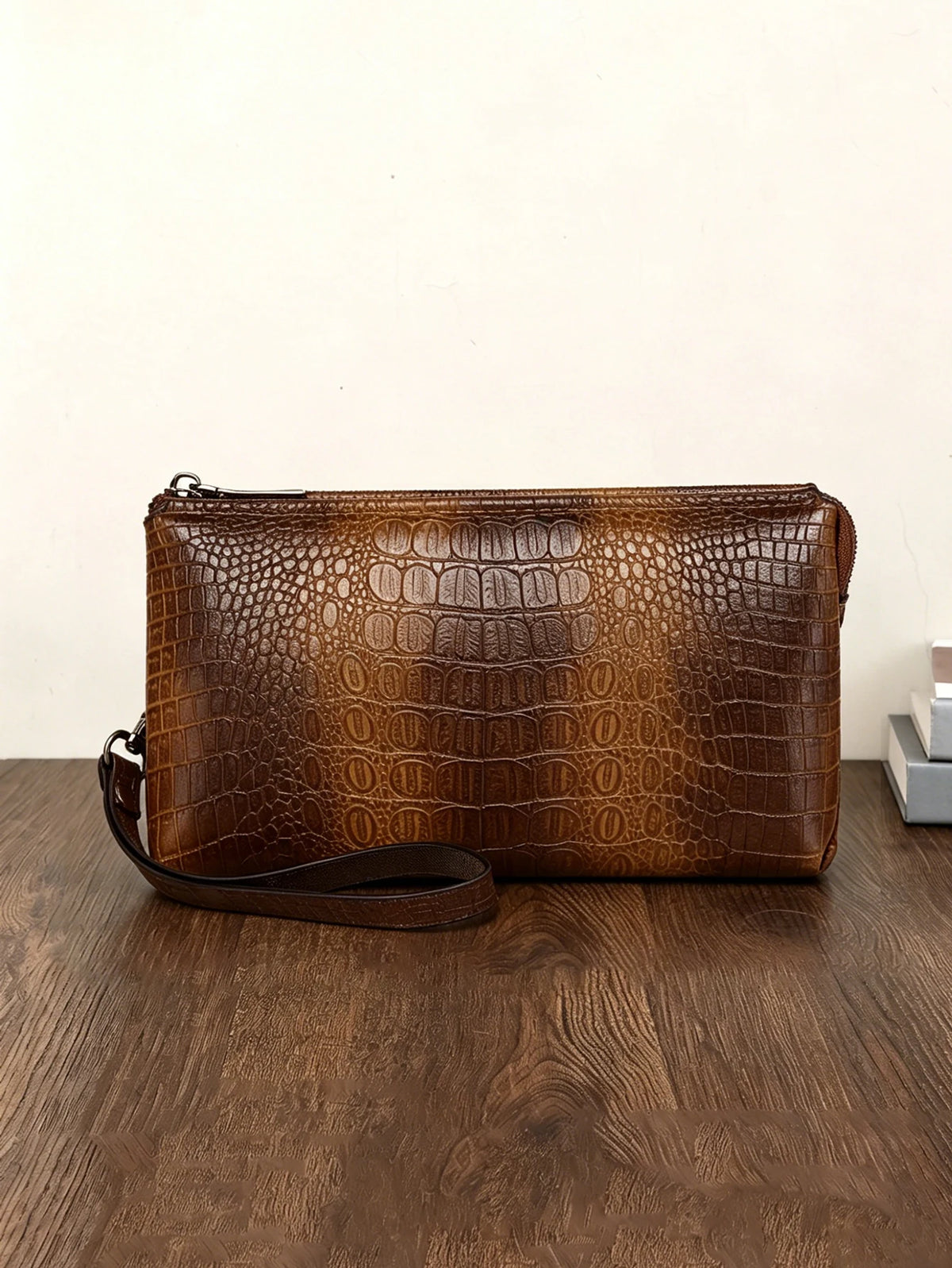 Clutch de estampado de cocodrilo marrón sobre una superficie de madera oscura.