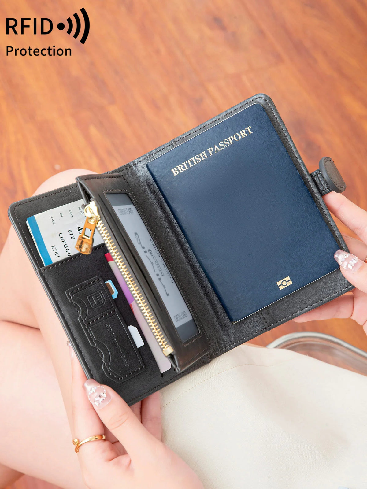 A hand holds an open black leather passport wallet displaying a British passport and other cards.