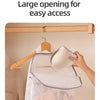 A hand is hanging a white honeycomb mesh laundry bag onto a wooden wall-mount hook.