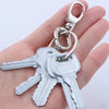 Silver metal swivel lobster claw clasps attached to a key ring being held in a hand.