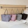 Four canvas tote bags with different leopard print patterns are hanging on a wooden bar.