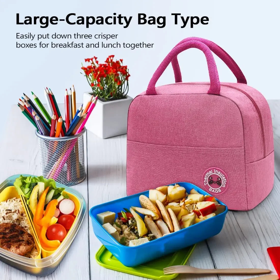 A pink insulated canvas lunch bag is shown next to a blue container filled with food and various writing tools.