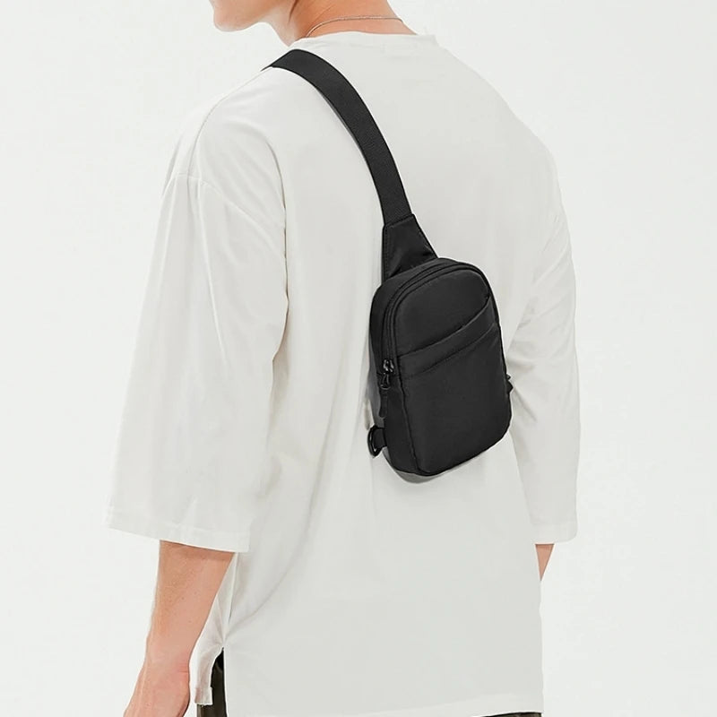 Una bolsa cruzada negra multifuncional se lleva en la espalda de una camiseta blanca.