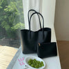 A black vintage large-capacity tote bag and a smaller black clutch bag displayed on a white surface.
