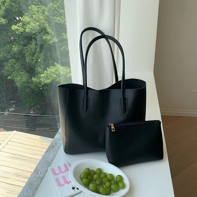 A black vintage large-capacity tote bag and a smaller black clutch bag displayed on a white surface.