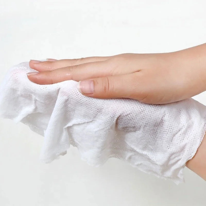 Une main tient une serviette de visage en coton compressé et réutilisable blanche.