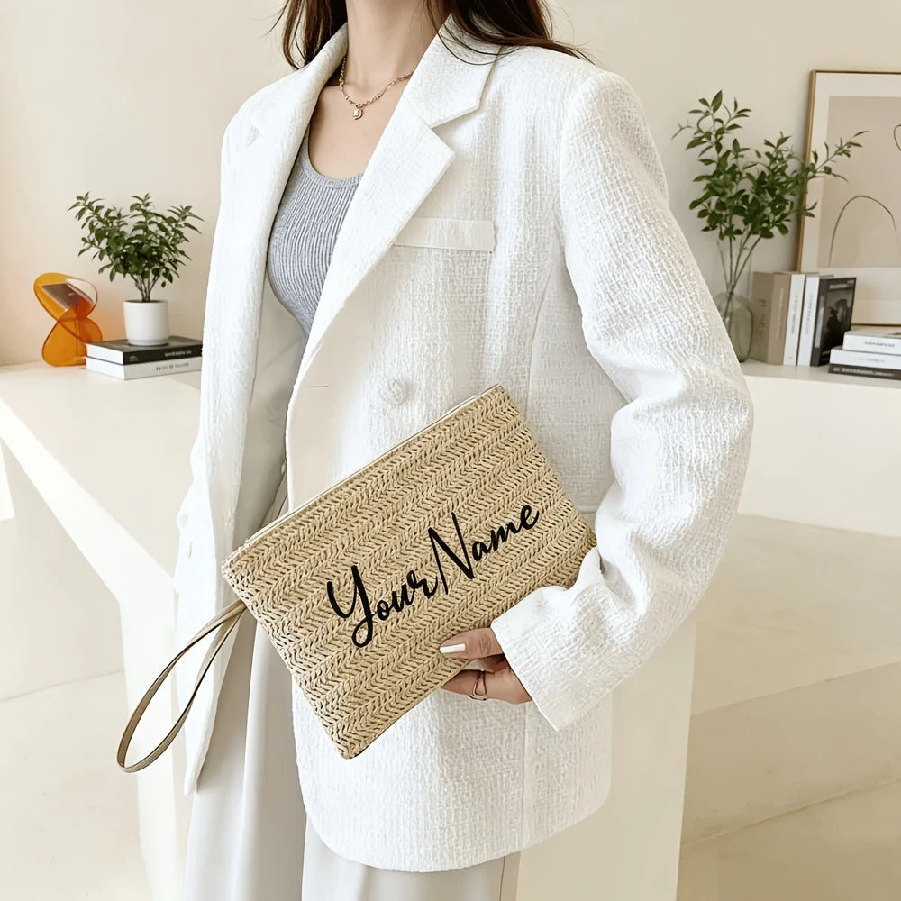 A woman holds a beige handwoven straw makeup bag with the name Your Name in it, wearing a white blazer.